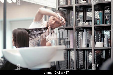 Moscow, Russia - Oct 10, 2019: Professional hairdresser working with client in salon. Male hair stylist and female customer in salon. Stock Photo