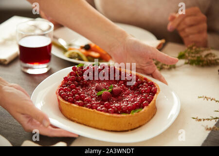 Close-up of woman putting berry sweet pie on the table during holiday dinner Stock Photo