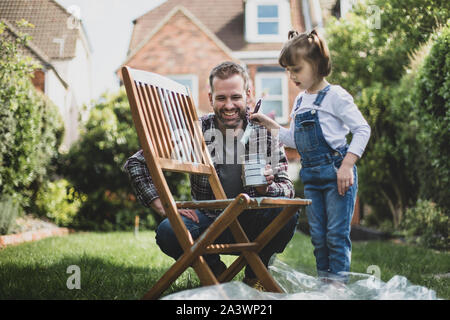 Father and Daughter painting garden furniture together Stock Photo