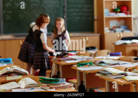 The children left their satchels and notebooks on the tables and went to recess. Three small students stayed in class to discuss the lessons Stock Photo