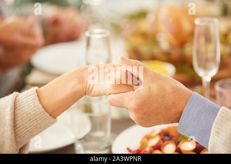 Close-up of family sitting at dining table and holding hands before the eating meal Stock Photo