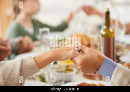 Close-up of senior couple holding hands and praying at dining table before eating the meal with family Stock Photo