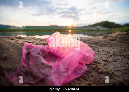 Cellophane package on the river bank. Environmental pollution.Garbage on the beach Stock Photo