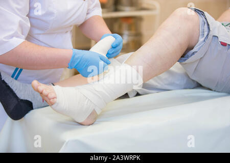 Nurse bandages the leg. Fracture of human lower limbs. Treatment of broken bones. Impose a gypsum. Patient surgical department. The doctor's hands Stock Photo