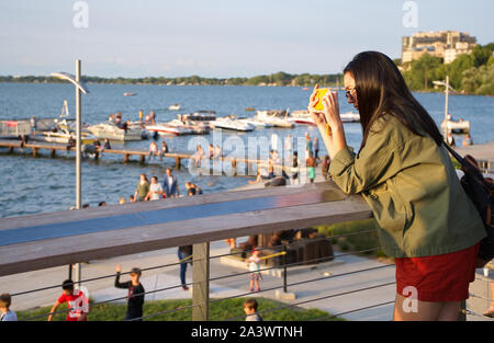 Madison, WI USA. Jul 2018.Young visitor taking cellphone pictures at the Alumni Park view deck. Stock Photo