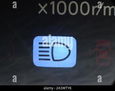 full beam headlights warning light on dashboard being used on vehicle driving  at night Stock Photo
