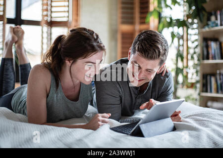 Young adult couple looking at a digital tablet together in bed Stock Photo