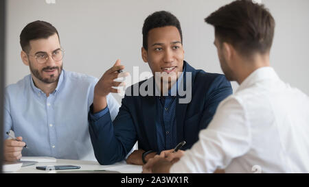Three diverse business men talking sit at negotiation table Stock Photo