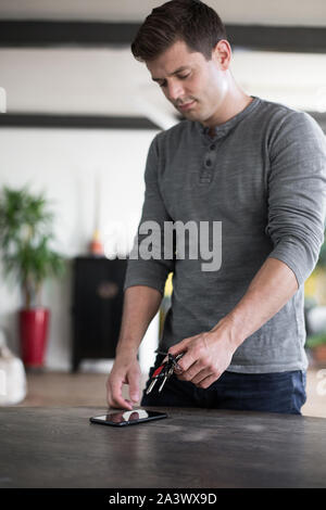 Adult male picking up keys and smartphone from table Stock Photo