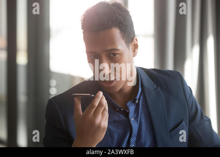 Serious african businessman speak activate voice assistant on smartphone Stock Photo