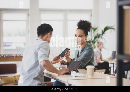 Freelancers looking at a smartphone in a coworking space Stock Photo