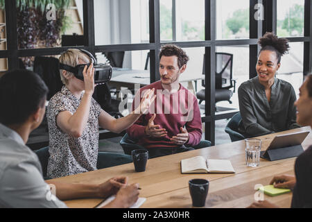 Coworkers discussing VR headset technology Stock Photo