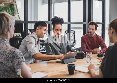 Coworkers in a meeting looking at a digital tablet Stock Photo