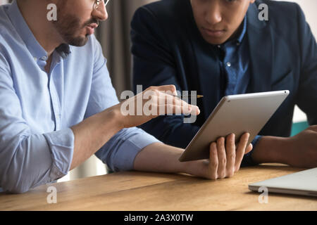 Diverse businessmen talking using digital tablet sit at desk, closeup Stock Photo