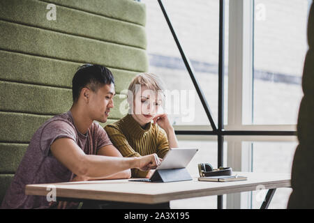 Coworkers in a meeting looking at a digital tablet Stock Photo