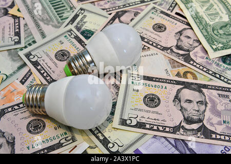 Two LED bulbs in the background of different countries currency notes.   Economy concept - image Stock Photo