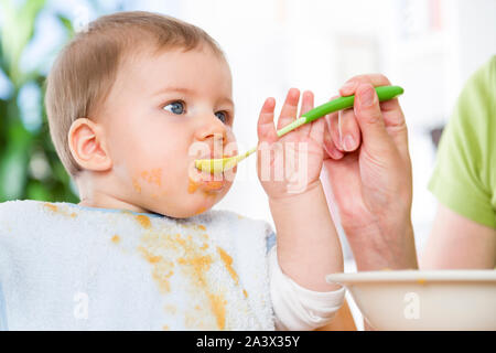 Close up of cute messy baby boy eating his meal. Stock Photo