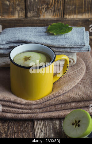 Yellow rural mug with apple hot drink and woolen scarf and socks,  hygge autumn or winter weekend holidays, still life Stock Photo