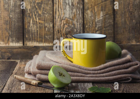 Yellow rural mug with apple hot drink and woolen scarf,  hygge autumn or winter weekend holidays, still life Stock Photo