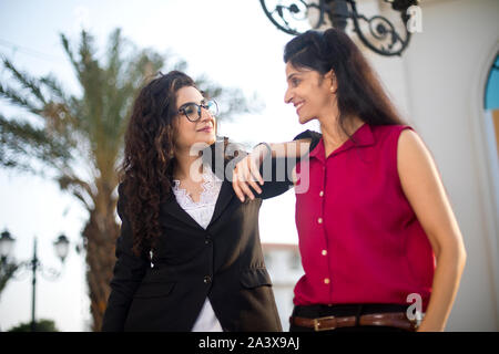Two happy female business colleagues having fun together outdoors in city Stock Photo