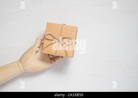 Wooden mannequin hand opens a gift in a box tied with twine. Gift background concept for holiday makers. Greeting card for christmas, birthday and new Stock Photo