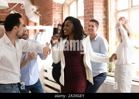 Happy diverse colleagues dance having fun in office Stock Photo