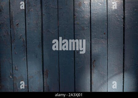 aged blue painted grunge wood texture background. Antique blue wood texture. Wooden planks shot in the sunlight at sunset. Old house is his wall. Peel Stock Photo