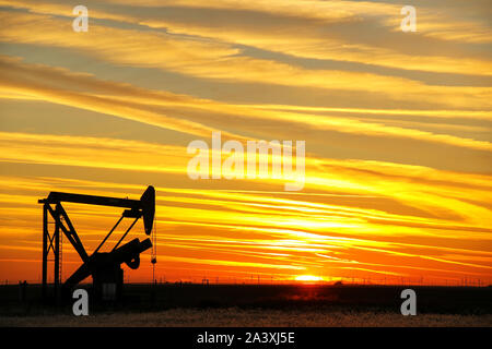Silhouetted pump jack in the oil field at sunset Stock Photo