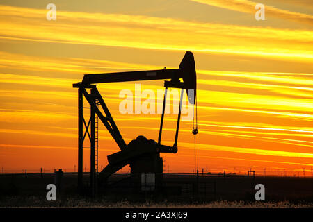 Silhouetted pump jack in the oil field at sunset Stock Photo