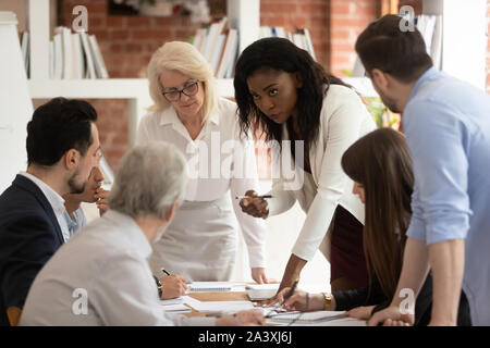 Focused multiracial employees brainstorm sharing ideas at briefing Stock Photo