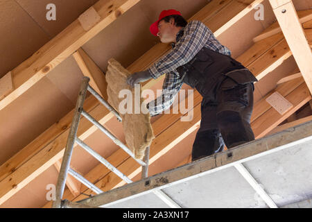 Construction worker thermally insulating eco wooden frame house Stock Photo