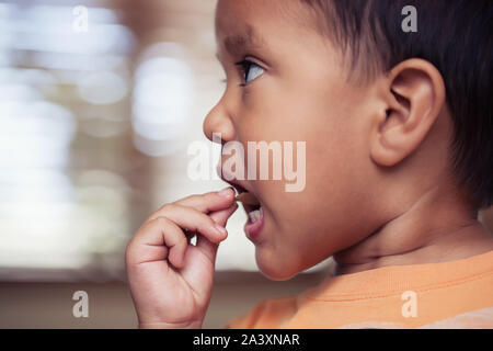 A profile view of a little kid putting a potato chip in his mouth to eat. Stock Photo