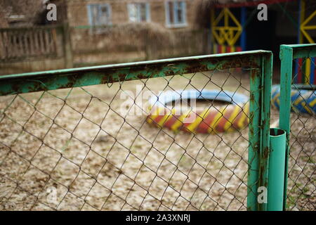 Old green mesh fence in autumn garden. Selective focus Stock Photo