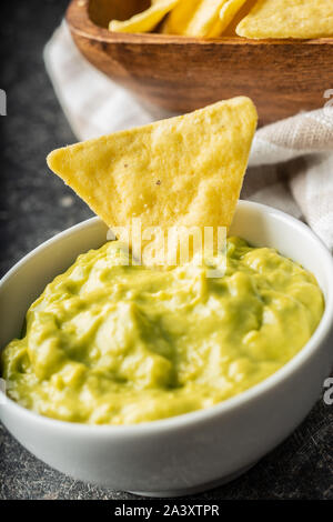 Corn nacho chips and avocado dip. Yellow tortilla chips and guacamole in bowl. Stock Photo