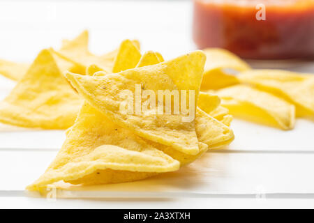 Corn nacho chips. Yellow tortilla chips on white table. Stock Photo