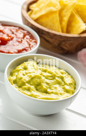 Sauces in bowl. Guacamole and tomato dip in bowl on white table. Stock Photo