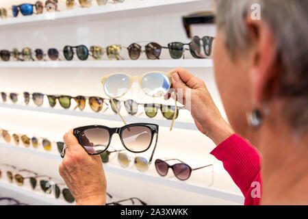 Optician, eyewear store, woman picking out sunglasses, Stock Photo