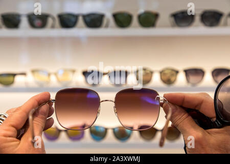 Optician, eyewear store, woman picking out sunglasses, Stock Photo