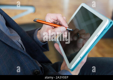 Male passenger working with a tablet computer at the airport with touchpen Stock Photo