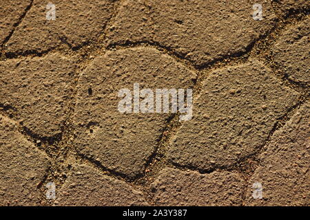 Road surface made of old asphalt with cracks. Stone texture with warm light. Top view Stock Photo