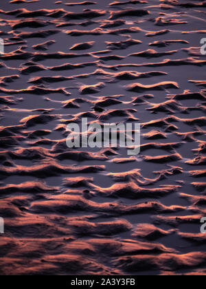 Sunset reflected in the sand patterns during sunset on the beach in Texel, The Netherlands. Stock Photo