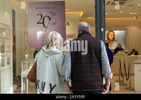 A middle aged couple looking in a shop window at goods for sale Stock Photo