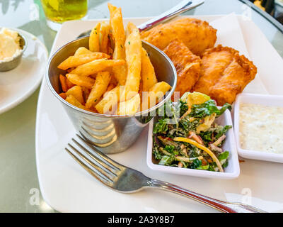 Fish and Chips. Fried fish in batter served with chips, sauce, vegetables, and ketchup Stock Photo
