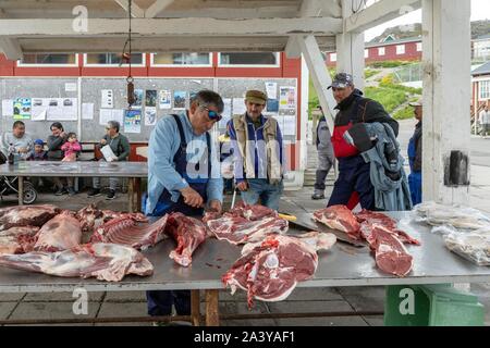 BUTCHER CUTTING UP THE CARCASSES OF MUSKOX AND DEER AT THE MEAT MARKET,  TOWN OF QAQORTOQ, GREENLAND, DENMARK Stock Photo