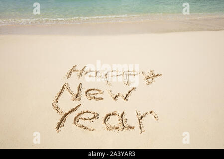Happy New Year Text Written On Sand Near The Sea At Beach Stock Photo