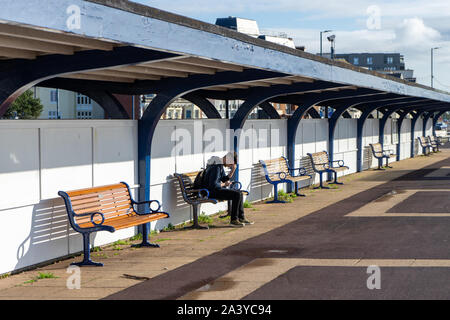 A young man sitting alone on a bench with his head in his hands Stock Photo