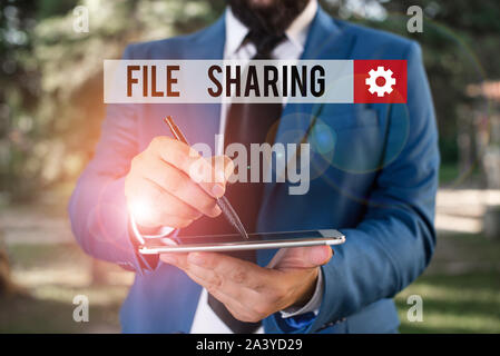 Text sign showing File Sharing. Business photo showcasing transmit files from one computer to another over a network Businessman in blue suite stands Stock Photo