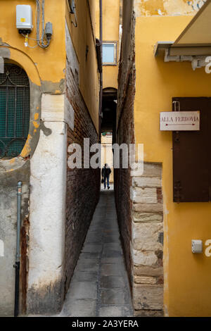 A man passing thought a typical narrow alley in the old city center of Venice, Italy. Stock Photo