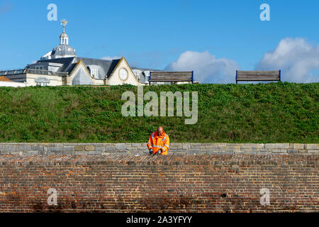 A bricklayer in High visibility clothing repairing a brick wall Stock Photo