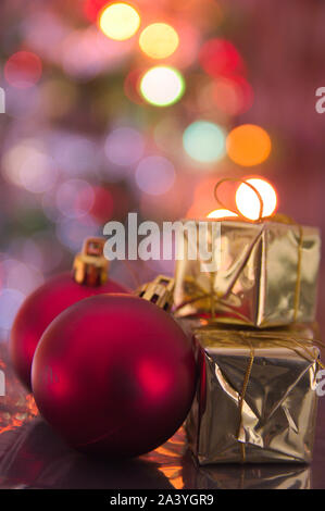 Christmas balls and golden gift boxes form the decoration of the Christmas tree, in the background in the form of a bokeh you can see colorful lights Stock Photo